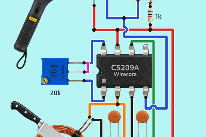 A CS209A chip with a blue 20 k trimmer beside it, two orange 2.2 nF disc capacitors, a copper search coil with a kitchen knife lying across it, a red LED with a 1 k resistor and a buzzer at the top, a 9 V battery and a handheld detector wand